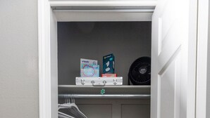 A small walk-in closet with a grey wall, a white door, and a metal rack with hangers. - Modern City Oasis: Pet Friendly | Downtown | Park (Little Rock)