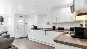 Una cocina moderna con armarios blancos, encimera de madera y una cafetera.