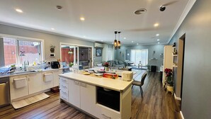 A modern kitchen with a central island, built-in appliances, and a dining area with a view to the living room.