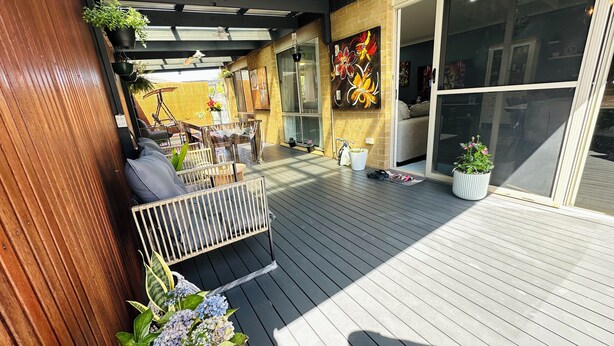 A wooden deck with a bench, potted plants, and a bicycle.