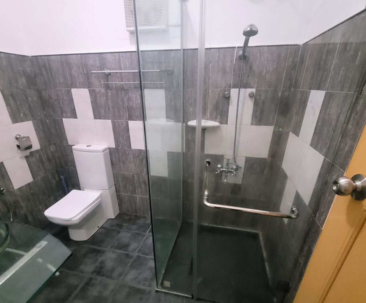Un baño con ducha envuelta en vidrio, inodoro y lavamanos.