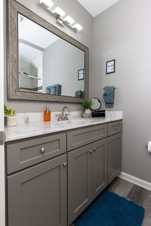 Une salle de bain avec un grand miroir, un lavabo doté d’un robinet moderne et un porte-serviettes.