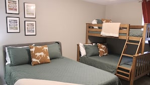 A room with two bunk beds, each with a mattress and pillows, and a lower bunk with a ladder. There are framed pictures on the wall. - Relax & Explore Downtown Little Rock (Little Rock)