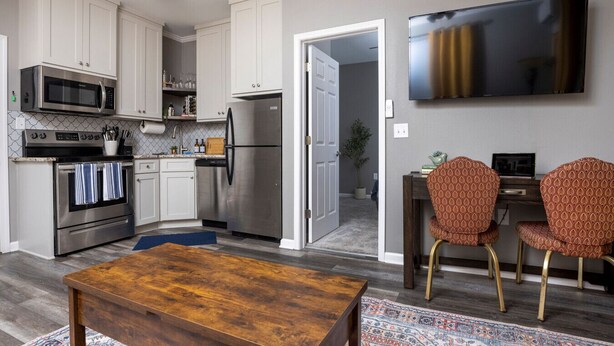 A modern kitchen with stainless steel appliances, a dining area with patterned chairs, and a large flat-screen TV. - Central Little Rock:Pet Friendly|Near Park |Museum (Little Rock)
