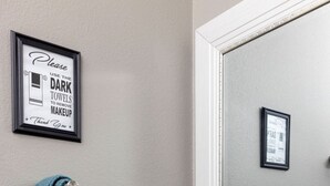 A bathroom with a marble countertop, a large mirror, a framed sign instructing to use dark towels for makeup removal, and a teal towel hanging on the wall. - Central Little Rock:Pet Friendly|Near Park |Museum (Little Rock)