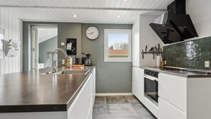 Een moderne keuken met een centraal eiland, een ingebouwde oven en een raam voor natuurlijk licht.