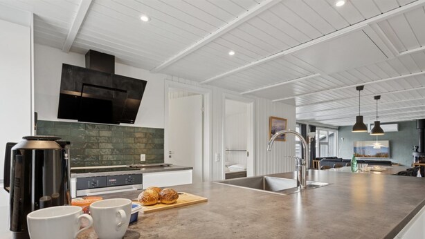 Een moderne keuken met een groot eiland, roestvrijstalen apparatuur en een groene achterwand.