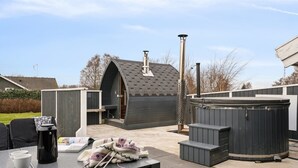 Een terras buiten met een tafel, stoelen, een jacuzzi en een overdekte zithoek.