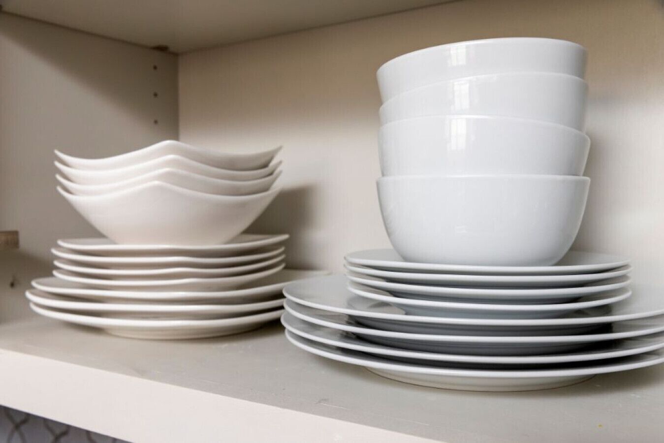 Une étagère remplie d’assiettes et de bols blancs.