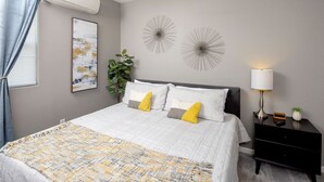 A bedroom with a bed, bedside table, lamp, and decorative wall art.