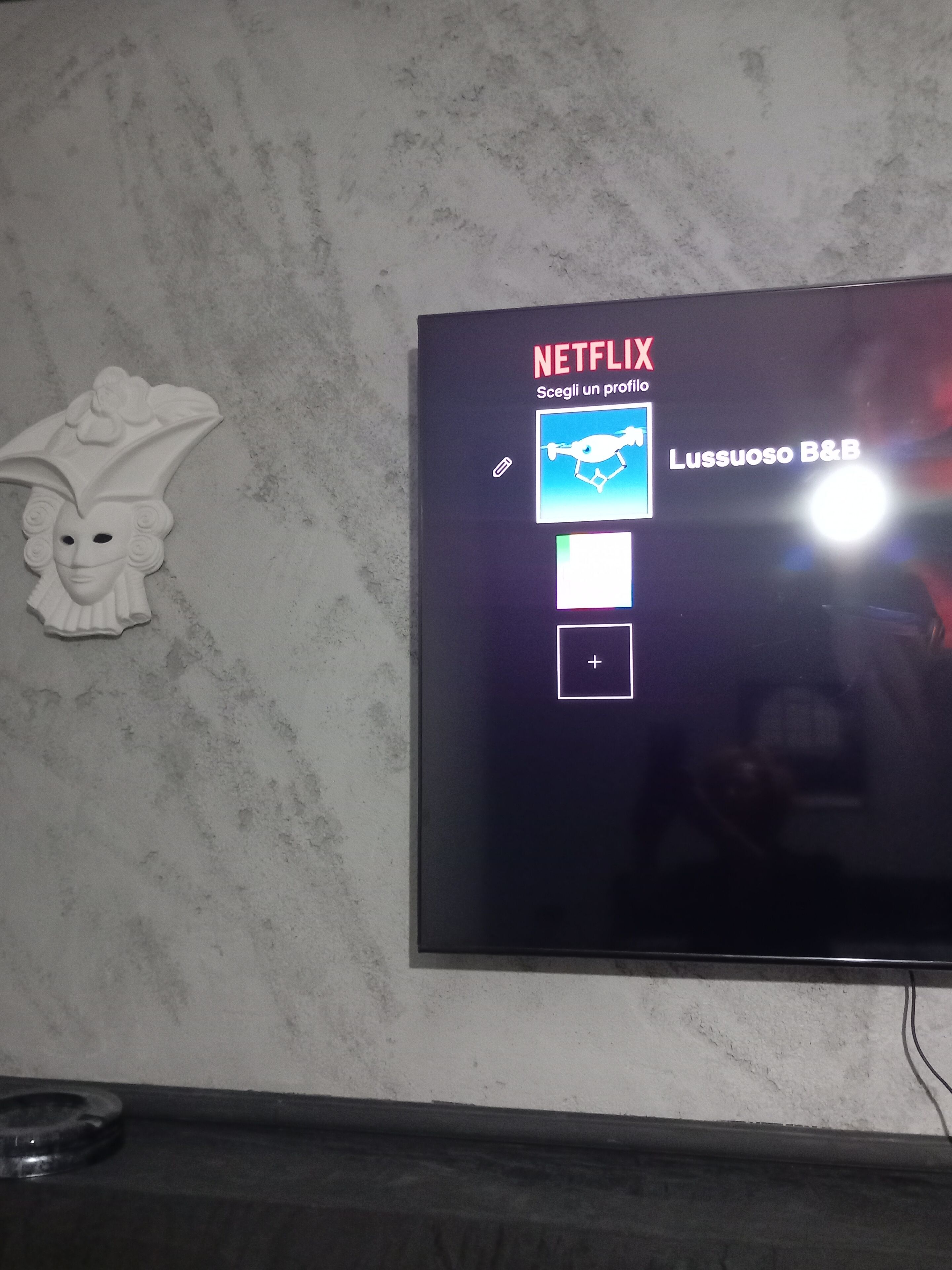 En tv som är monterad på en vägg, med Netflix-logotypen och en skärm för att välja användarprofil.