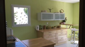 Een keuken met een raam, kastjes, een aanrecht en een spoelbak.
