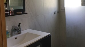 Een badkamer met een wit wastafel, een spiegel en een douchehoek.