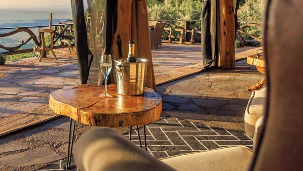 Una terraza de madera con una mesa y sillas, con vistas a un paisaje pintoresco.
