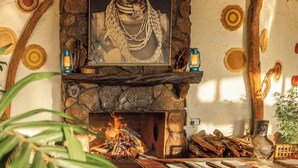 Una habitación acogedora con chimenea de piedra, un retrato enmarcado sobre ella y un sofá cómodo con una mesa frente a él.