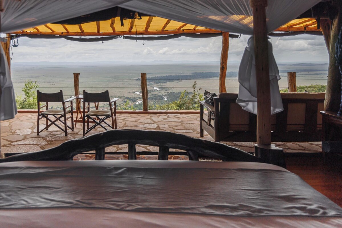 Una cama con vista a un paisaje a través de una pérgola de madera.