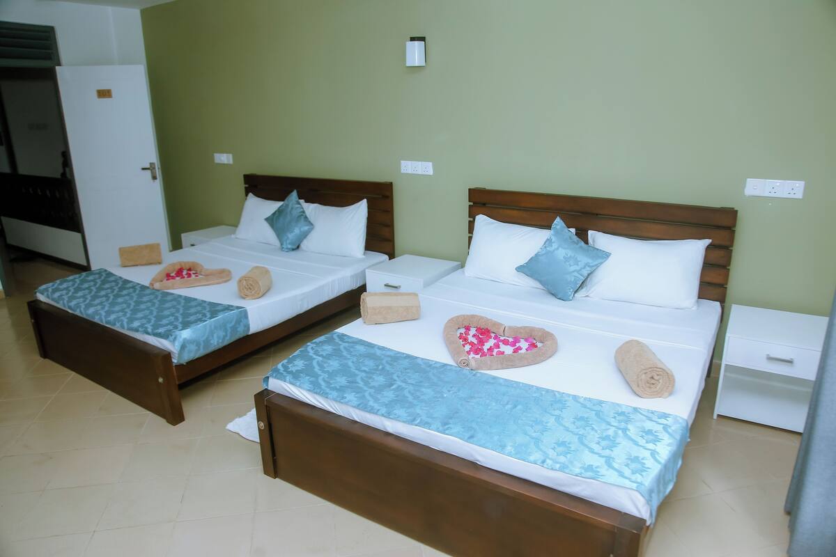 Dos camas individuales con estructura de madera, ropa de cama blanca y colchas estampadas en azul.
