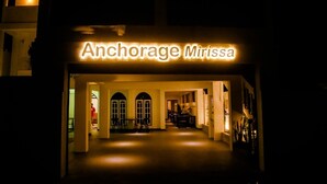 The entrance to Anchorage Mirissa with a warm illuminated sign, a central arched doorway, and a hallway leading inside. - Anchorage Mirissa (Mirissa)