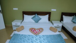 A hotel room with two beds, each with a wooden headboard, white nightstands, and a blue floral bedspread. - Anchorage Mirissa (Mirissa)