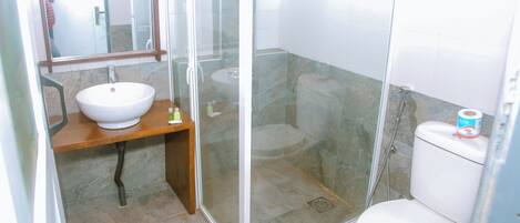 Un baño con cabina de ducha de vidrio, lavamanos blanco y retrete.
