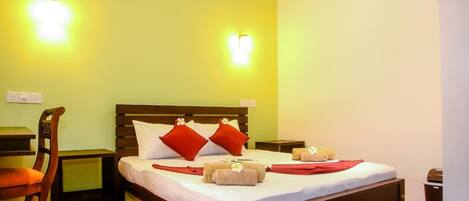 A hotel room with a wooden bed, two bedside tables, a chair, and a small desk.