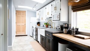 Une cuisine moderne avec des armoires blanches, un plan de travail en bois et une fenêtre équipée de stores.