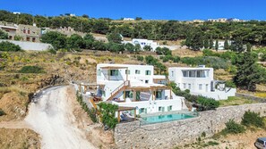Una villa moderna con piscina, mura in pietra e vista sulla collina.