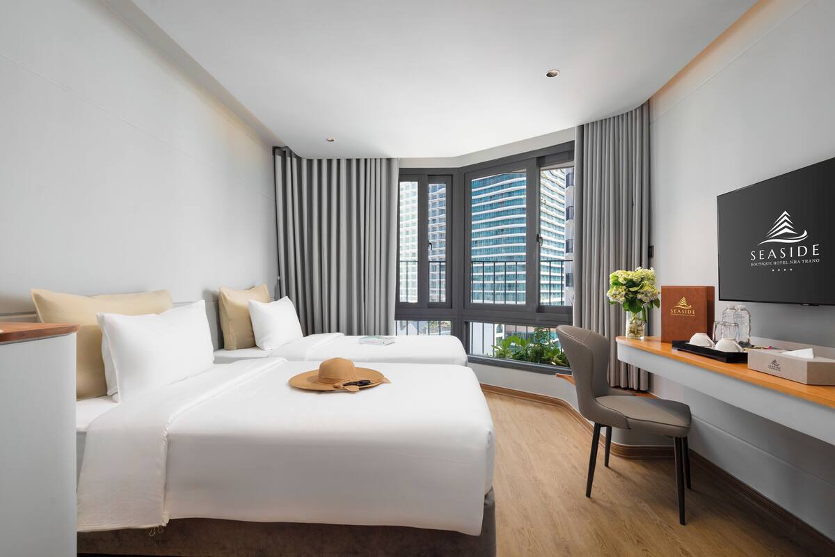 A hotel room with a bed, a desk, a chair, and a TV.