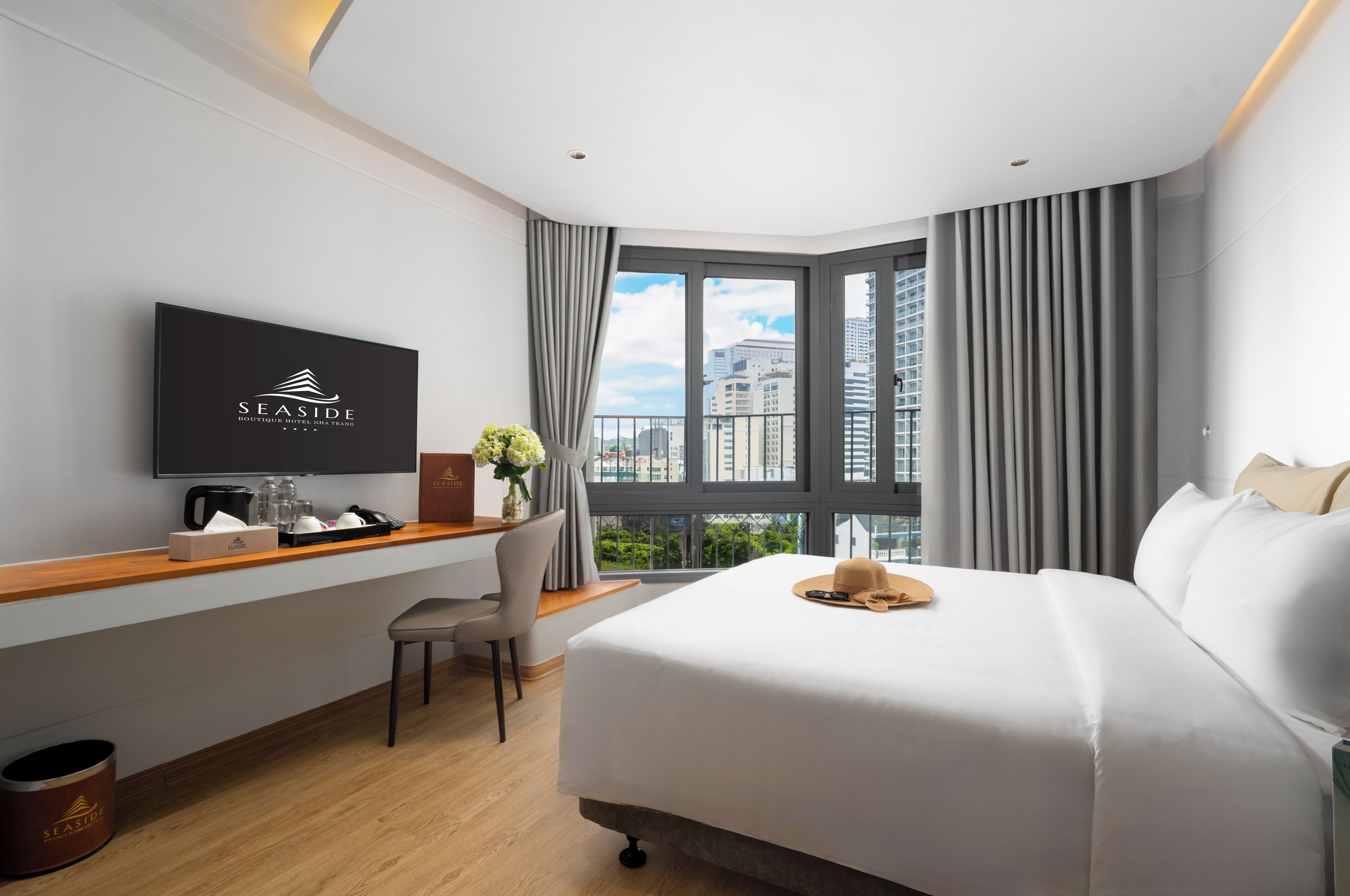 Une chambre d’hôtel avec un lit, un bureau avec une télévision, une chaise et une fenêtre avec des rideaux.