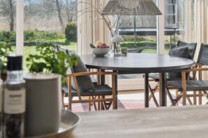 A round dining table with chairs, a bowl of fruit, a glass, and a lamp. - Lovely and cozy cottage with a beautiful terrace (Idestrup)