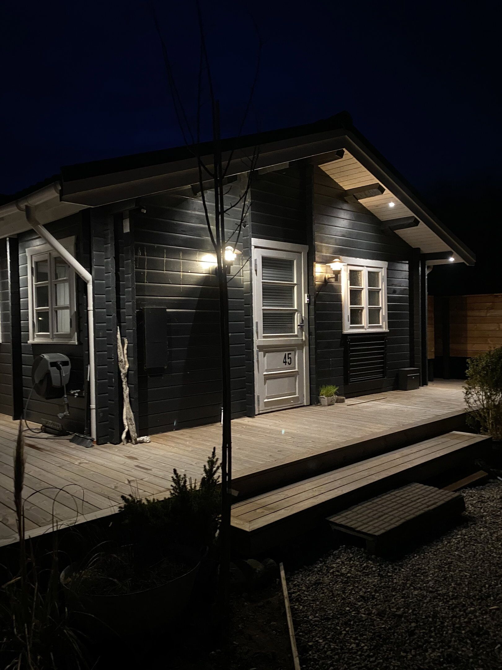 Een donker houten huis met een veranda, een garagepoort en een brievenbus.