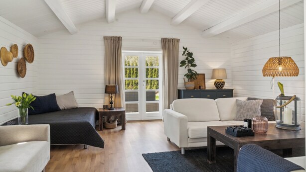 A room with a bed, sofa, coffee table, and a window with curtains.