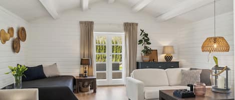 A room with a bed, sofa, coffee table, and a window with curtains.