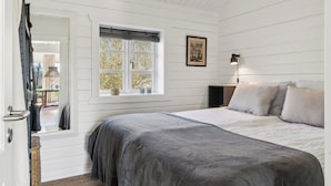 A bedroom with a bed, a window, a lamp, and a framed picture on the wall.