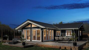 A modern house with a patio, sliding glass doors, and outdoor furniture.