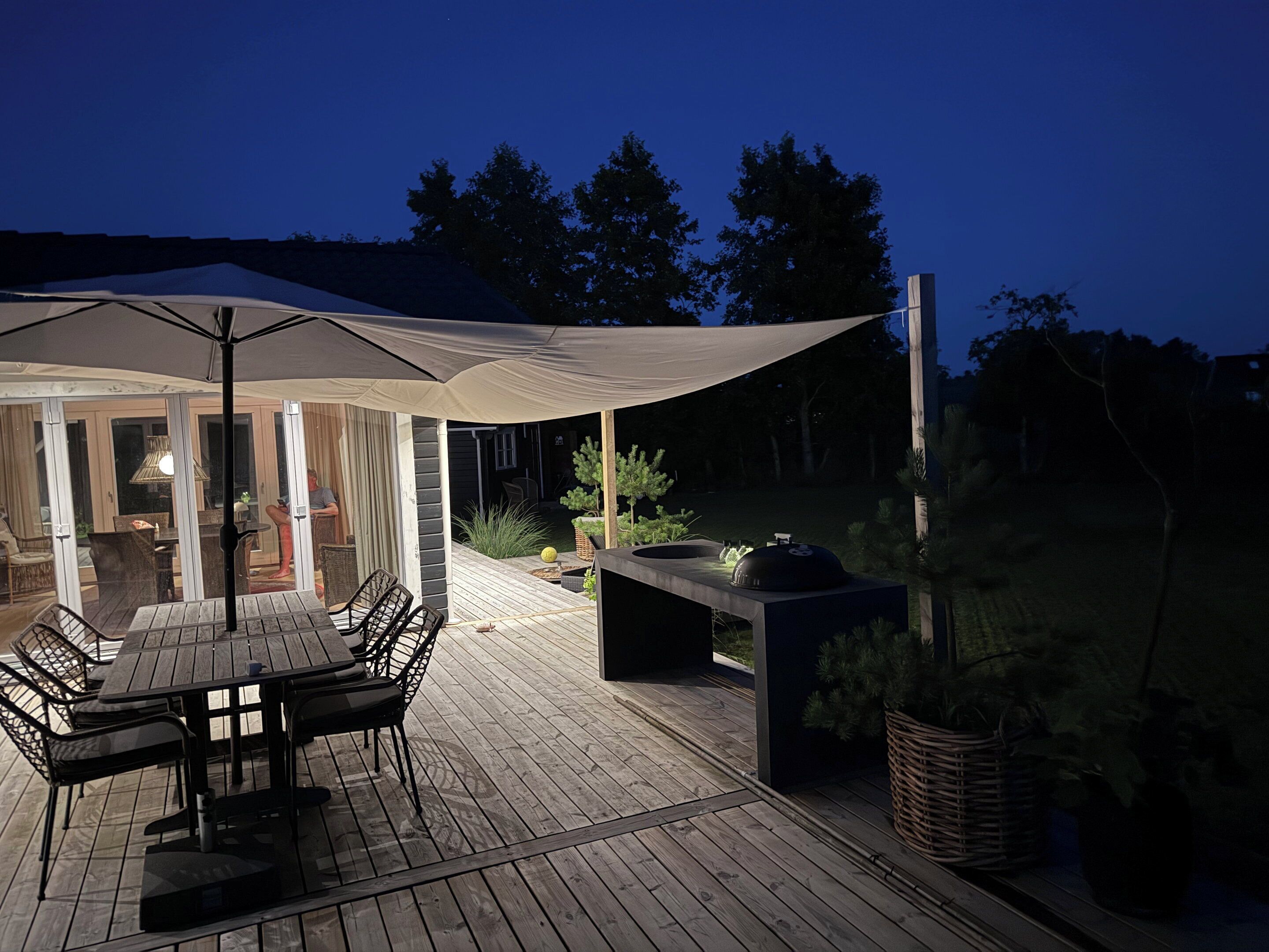 An outdoor patio with a table and chairs, a grill, and a covered seating area.