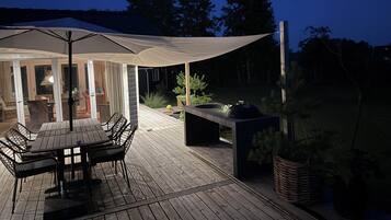 An outdoor patio with a table and chairs, a grill, and a covered seating area.
