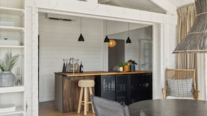 A modern kitchen with a wooden island, pendant lights, and a dining area with a dark table.