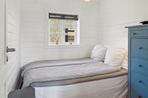 Un dormitorio con una cama, una ventana con vistas y un aparador azul.
