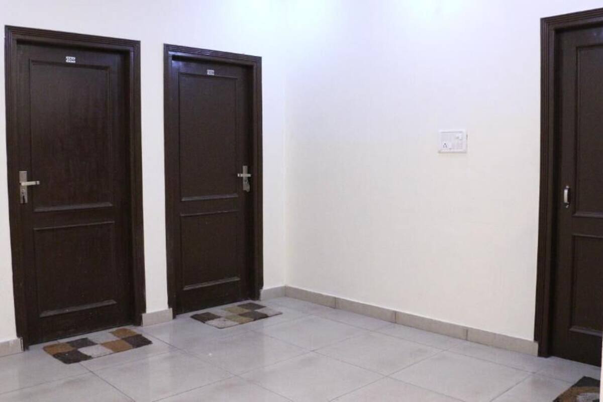 A hallway with three dark wooden doors, white walls, and a tiled floor.