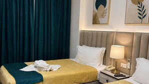 Een hotelkamer met twee bedden, een nachtkastje met een lamp en kunst aan de muur.