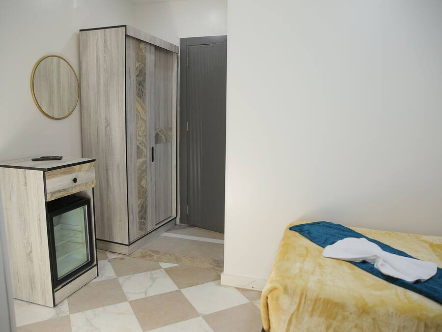 Ein Schlafzimmer mit Bett, Kleiderschrank, Spiegel und einem integrierten Minikühlschrank.
