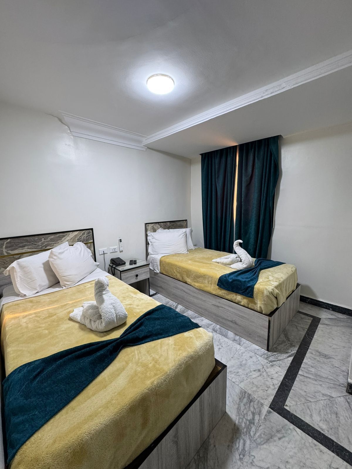 Ein Hotelzimmer mit zwei Betten, einem Nachttisch, einem Schreibtisch und einem Badezimmer.