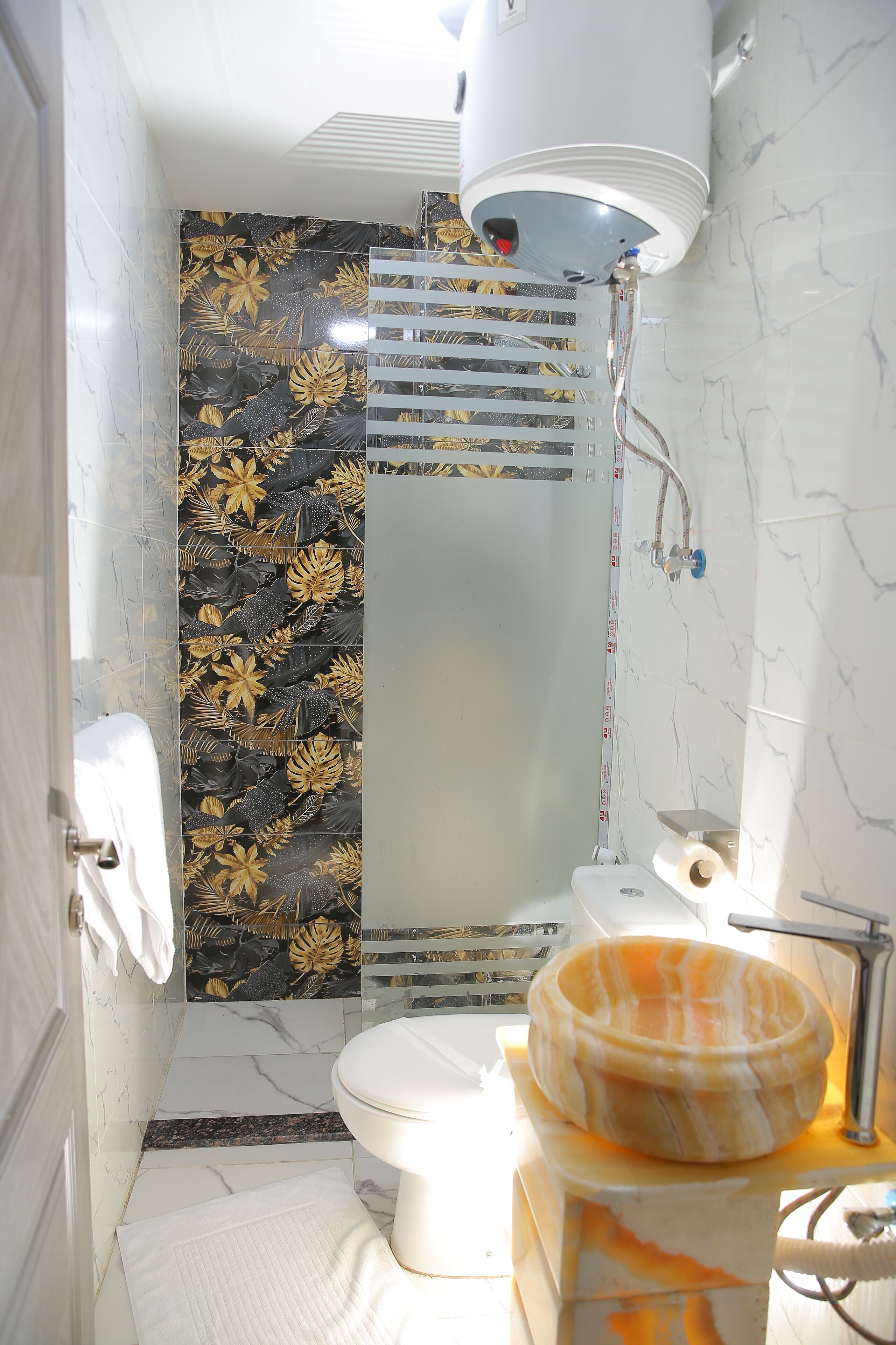 A bathroom with a toilet, a sink, a shower, and a decorative wall.
