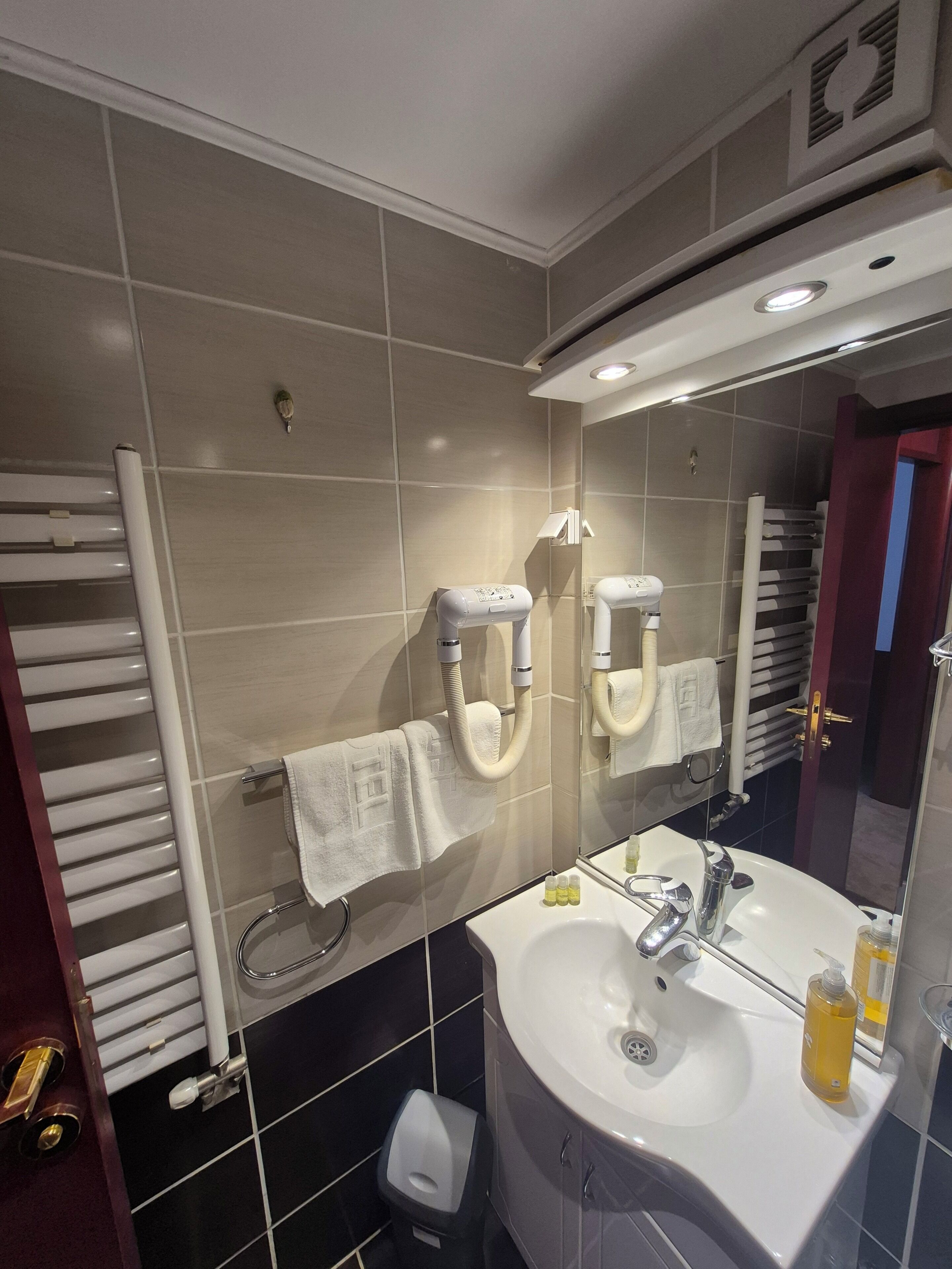 Un baño moderno con un espejo grande, un lavabo blanco y dos dispensadores de toallas.