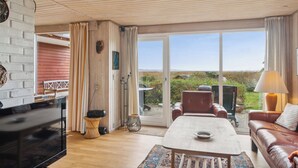 Een woonkamer met een televisie, een bank, een salontafel en uitzicht door een glazen deur.