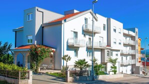 A modern multi-story residential building with balconies, a paved courtyard, and a clear blue sky. - Pension Silvia (Medjugorje)