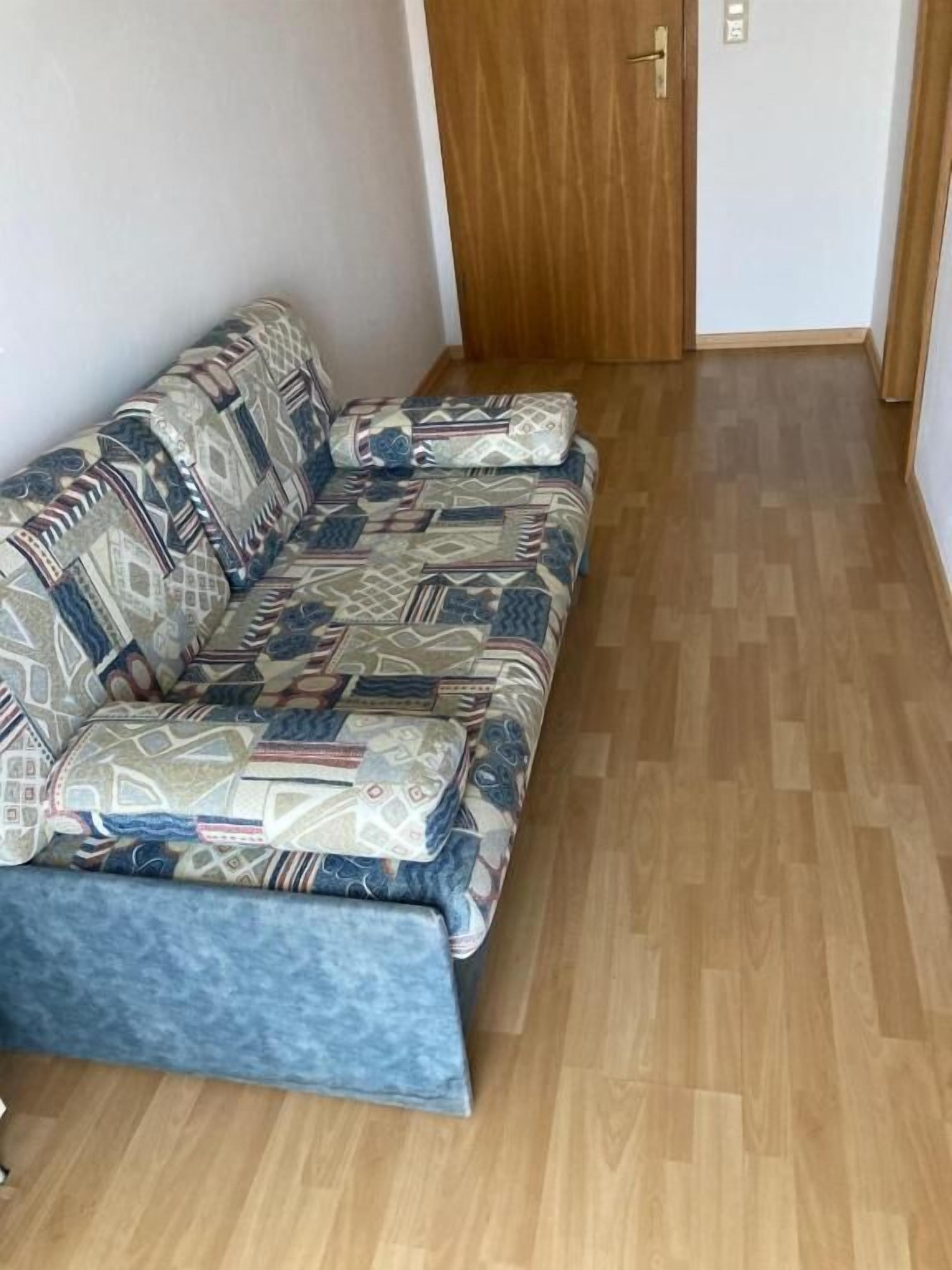 Una stanza con un divano decorato e un pavimento in legno.