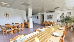 A dining area with long tables set for a meal, wooden chairs, and a potted plant. - Pension Silvia (Medjugorje)