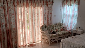 A bedroom with a floral-patterned sofa, a bed, and curtains.